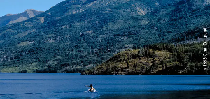 Lago del sur, con la ladera de la montaña de fondo. En el lago se ve a una persona en canoa. Argentina